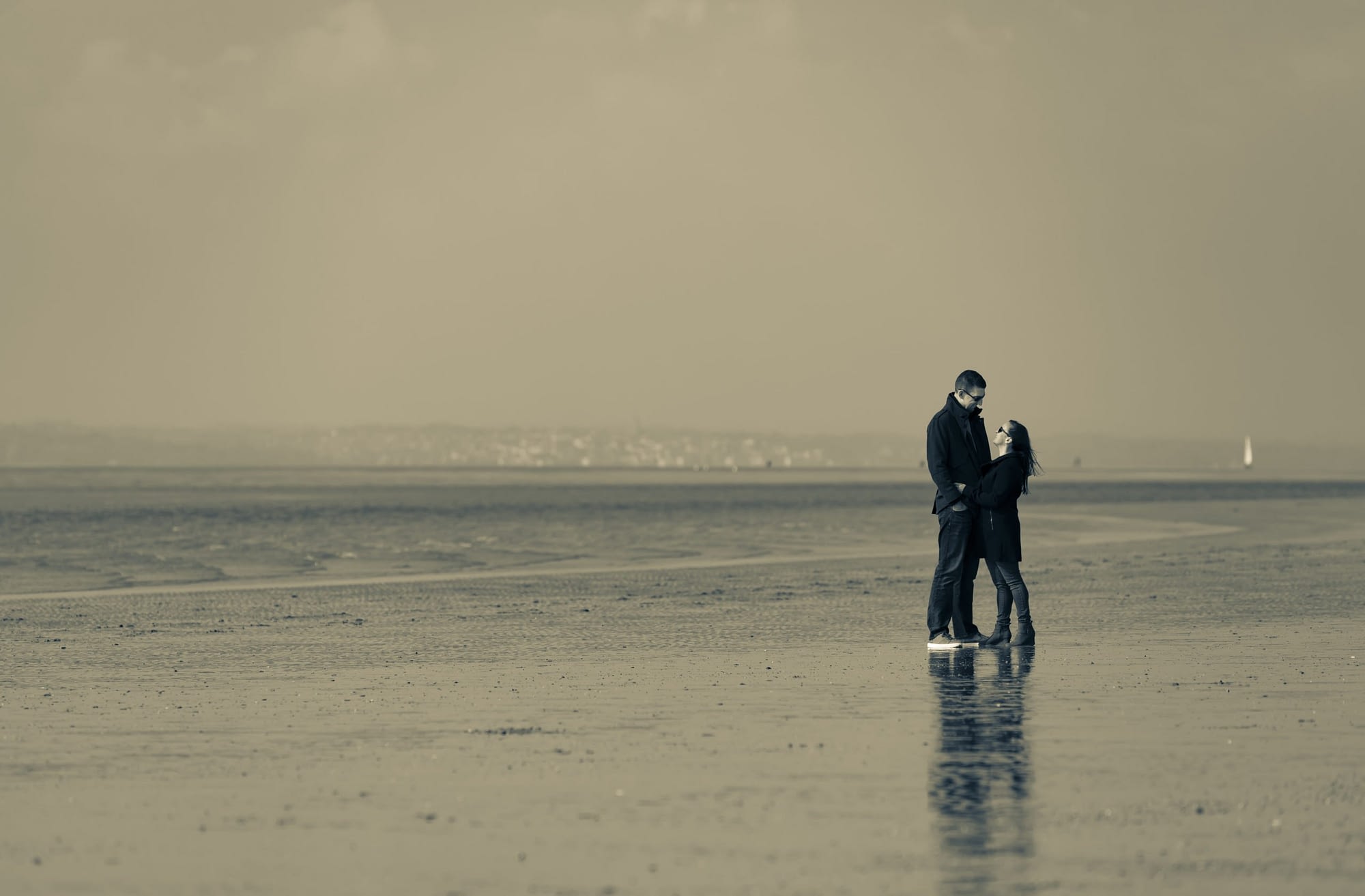couple standing together on a beach with the tide out