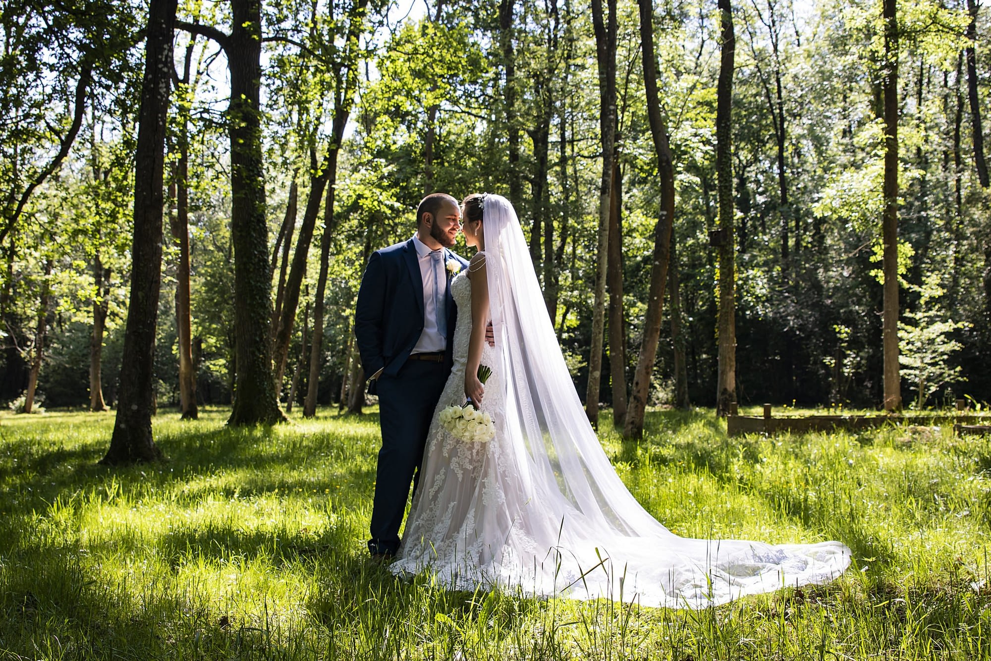 couple standing together in a forest clearing on a sunny day