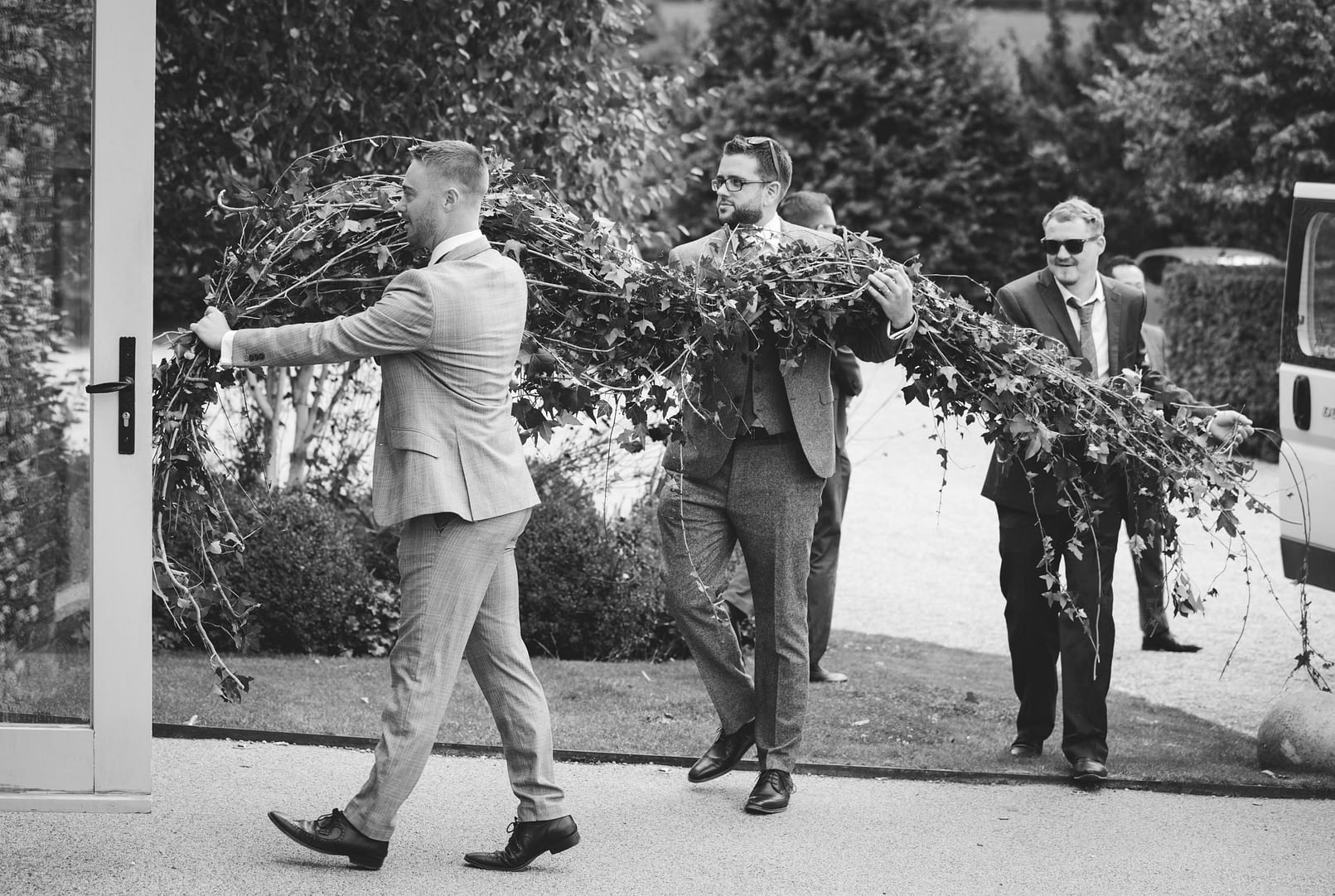 groomsmen carrying ivy outside