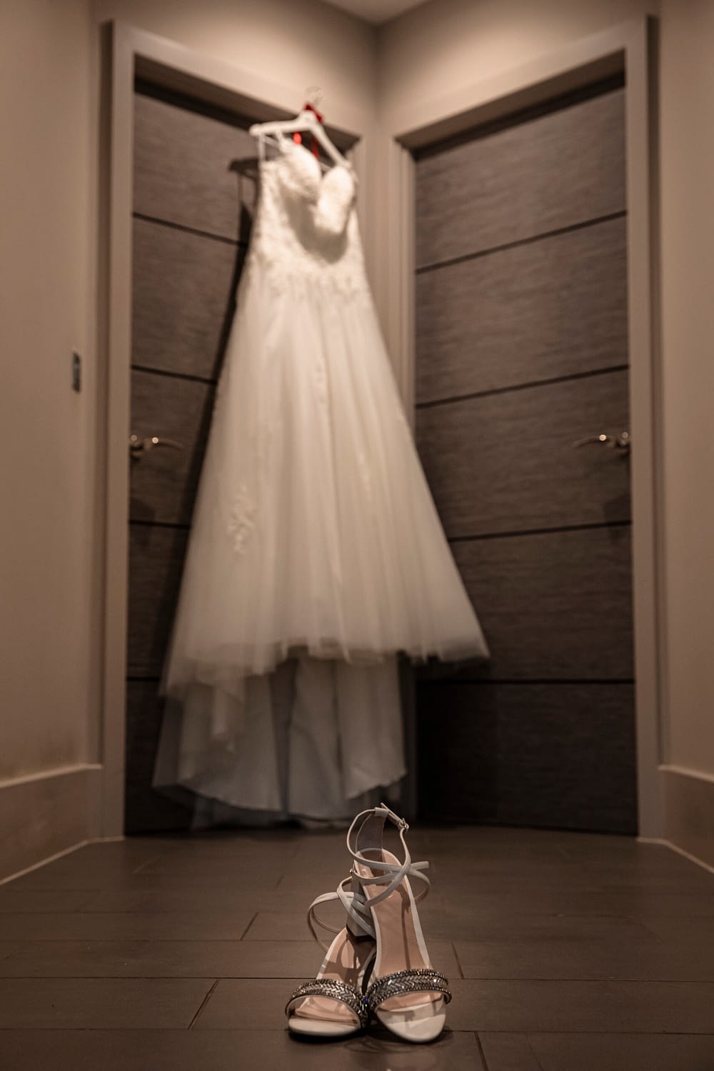 wedding dress hanging up with shoes on floor