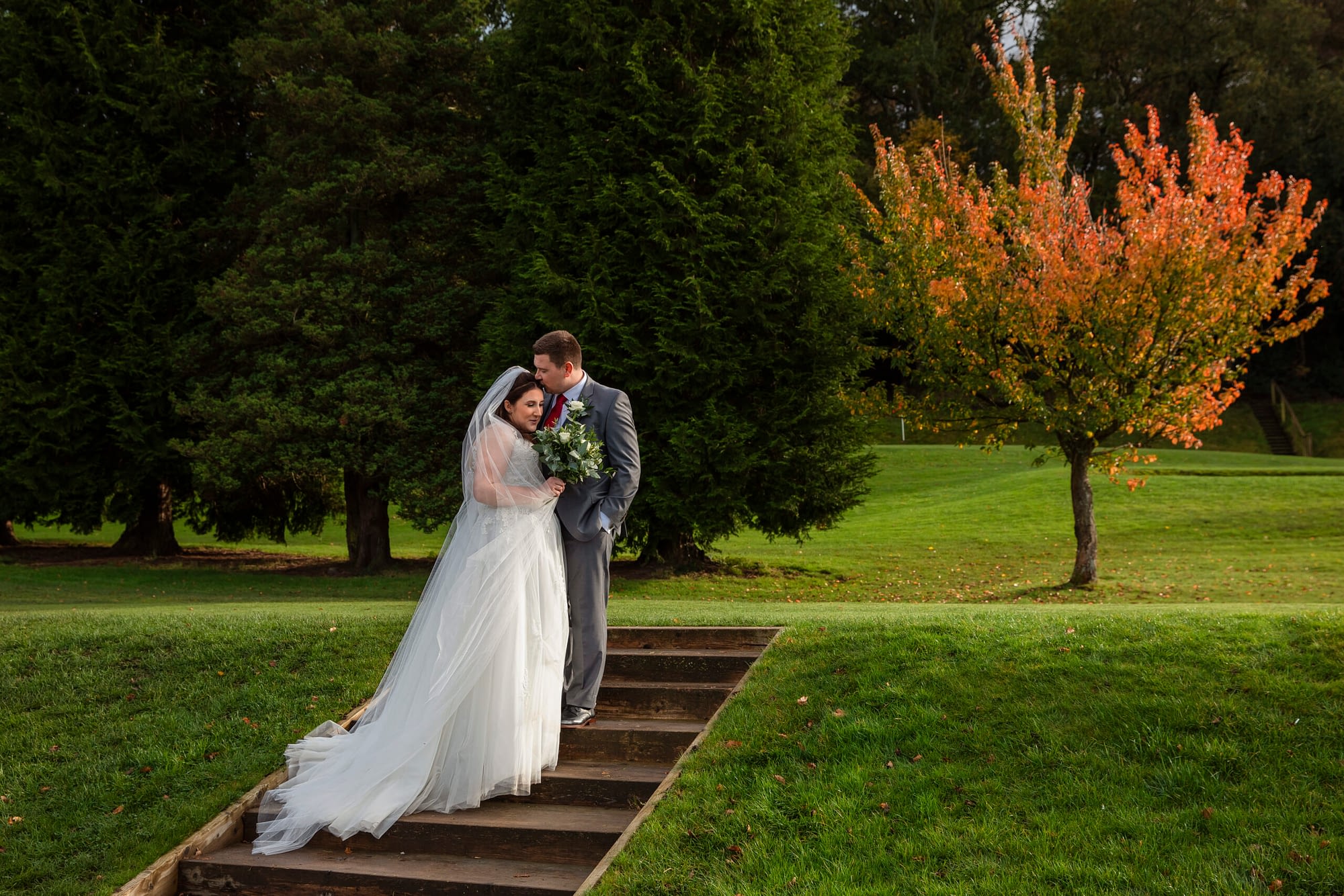 bride and groom standing together outside on steps with trees
