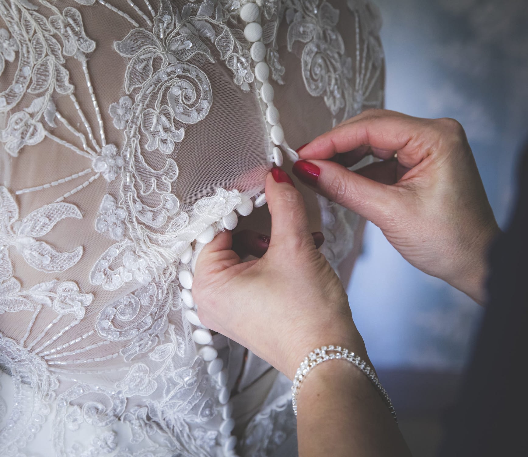 close up of bridal gown being buttoned up at the back