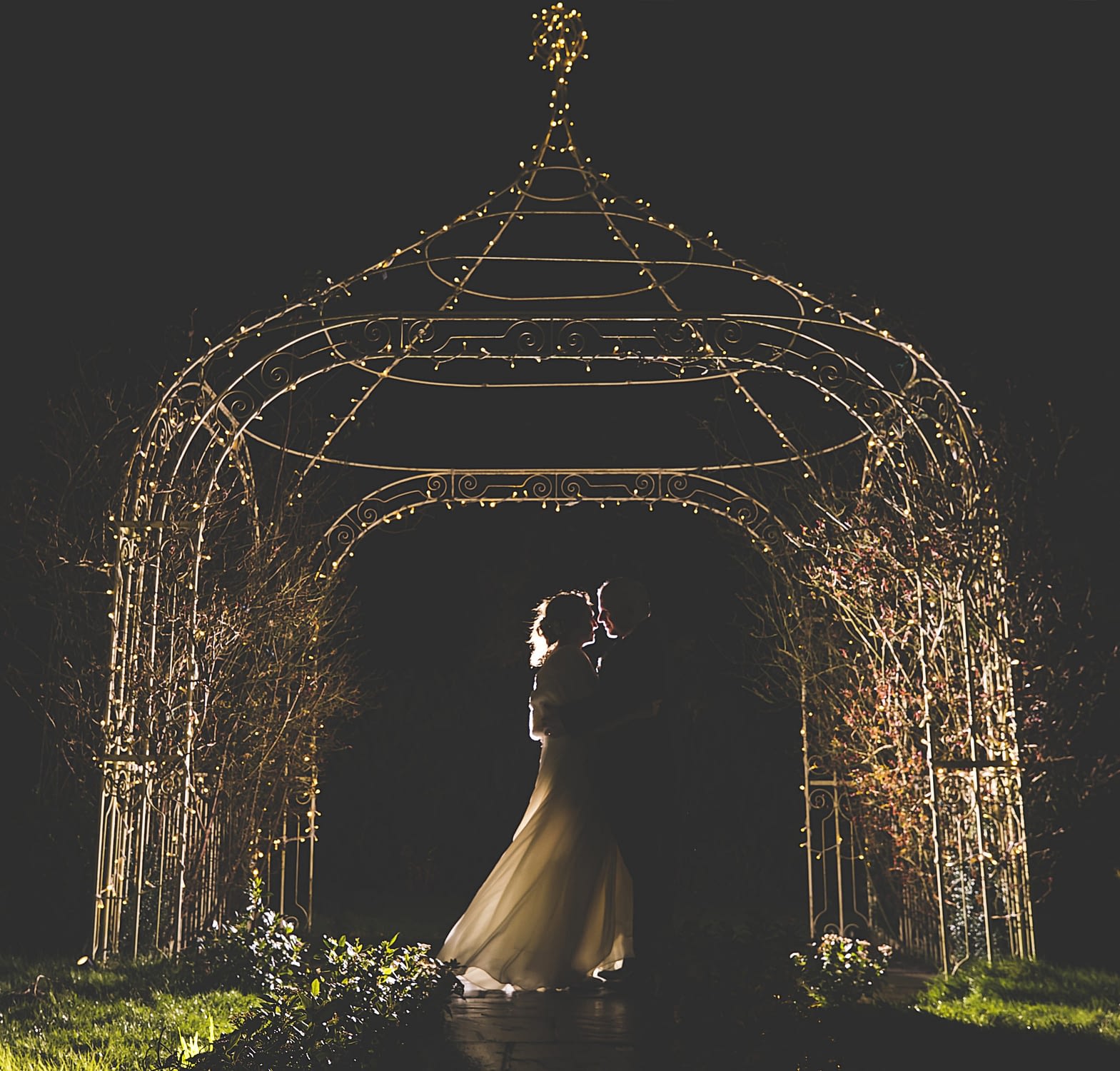 bride and groom at night with fairy lights on pagoda 