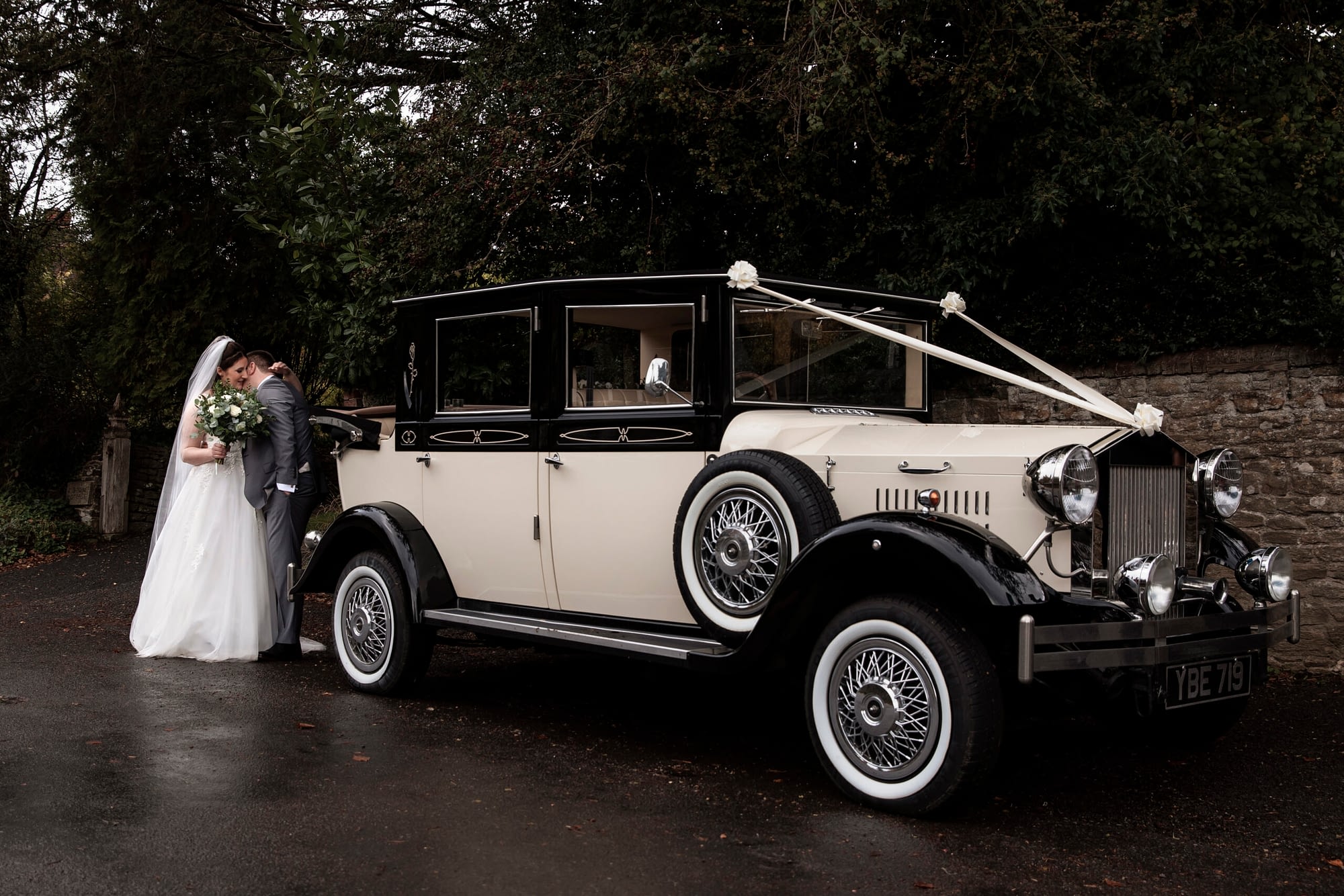 bride and groom standing next to old car